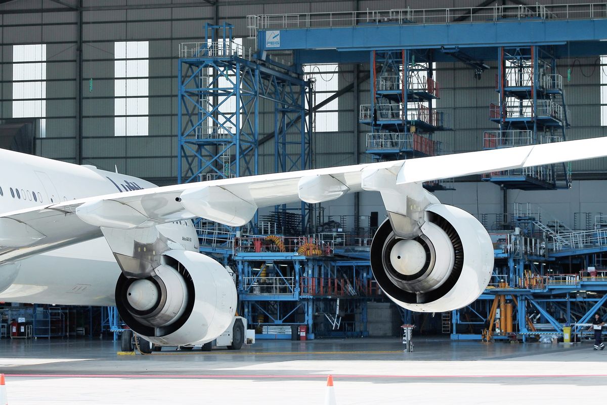 Wide-body aircraft engines and wing in a maintenance hangar, where AS9100 aerospace quality management applies